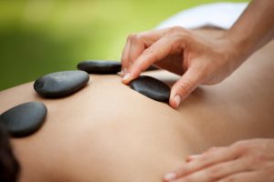 A woman getting a warm stone massage at a spa. You may also like: